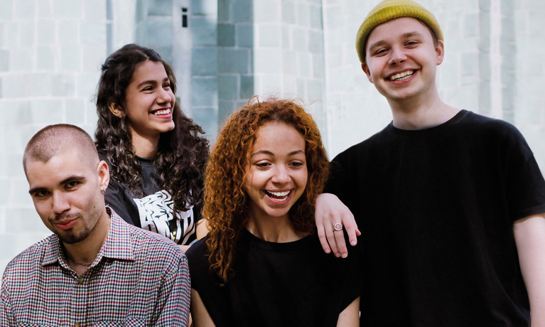 A group of students smiling at the camera outside.