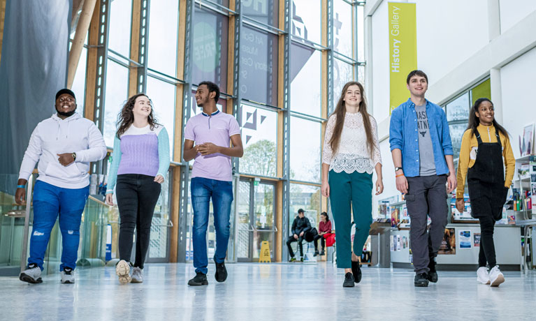 A group of students walking through the large bright foyer of the Herbert Art Gallery and Museum in Coventry.